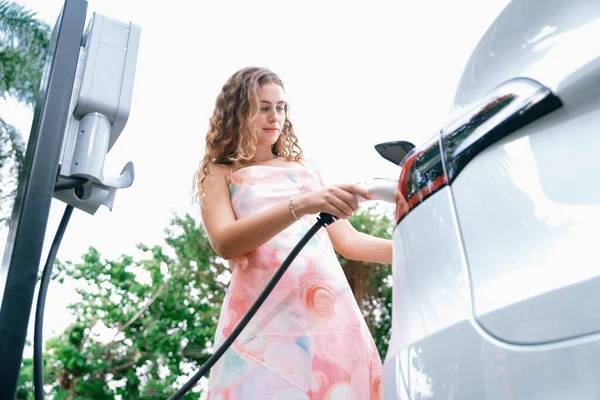 环保意识强的妇女从电动汽车充电站为现代电动汽车充电 电动汽车技术被用作未来可持续发展的替代交通工具 同步操作 — 图库照片