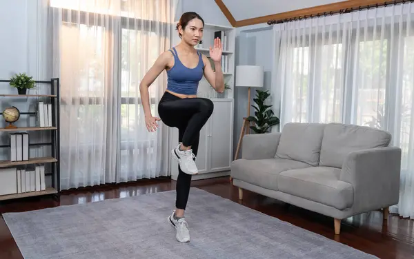 Enerjik ve güçlü atletik Asyalı kadın evinde koşuyor. Formda fiziğin takibi ve ev çalışması ve eğitimle sağlıklı yaşam tarzına bağlılık. Kuvvetli