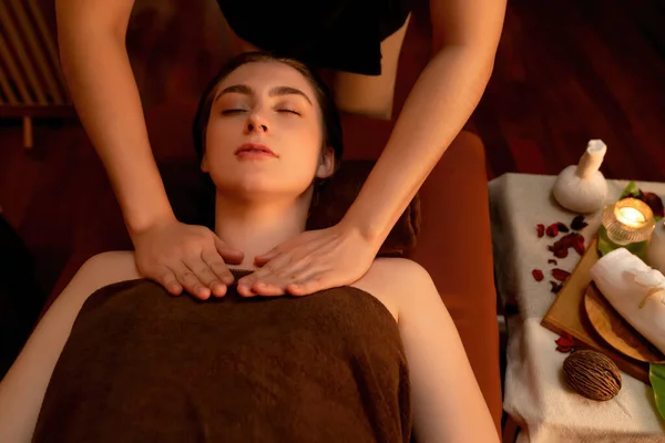 Top view woman customer enjoying relaxing anti-stress spa massage and pampering with beauty skin recreation leisure in warm candle lighting ambient salon spa at luxury resort or hotel. Quiescent