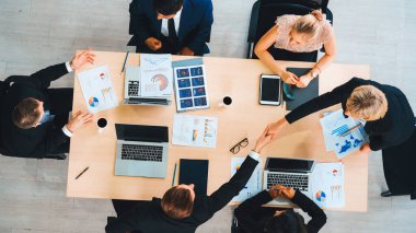 İş adamları grup toplantısı ofiste yukarıdan çekildi. İş kadınları, iş adamları ve ofis çalışanları toplantı masasında proje planlama belgeleriyle takım konferansında çalışıyorlar. Jivy