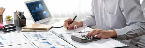 監査役は ラップトップ画面のBiダッシュボードを使用してオフィスで計算機で予算を計算します 会計事務所の専門会計士が収益性の高い収入のための財務書類を分析する — ストック写真