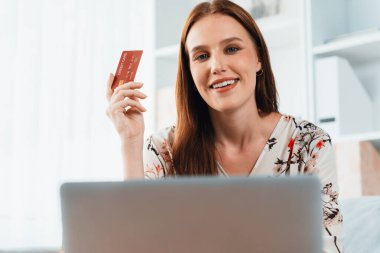 Genç mutlu kadın internetten alışveriş yaparak ürün satın alırken aynı zamanda internet üzerinden online ödeme sistemi ile çevrimiçi mağaza platformundan en yüksek siber güvenlik tarafından korunan ürünler sipariş ediyor.