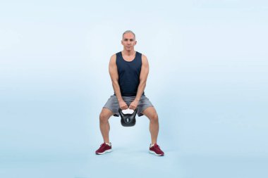 Vücut uzunluğu tam, atletik ve sportif yaşlı bir adam izole edilmiş arka planda vücut çalışması için kettlebell ile hiçbir şey yapmıyor. Emeklilikten sonra sağlıklı, aktif bir fiziğe ve vücut bakımına sahip. Etki