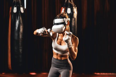 VR ya da sanal gerçeklik ile kadın boksör eğitimi almış, boks simülatöründeki yeteneğini geliştirmek için kontrolör kullanan bir VR kulaklık takıyor. Impetus