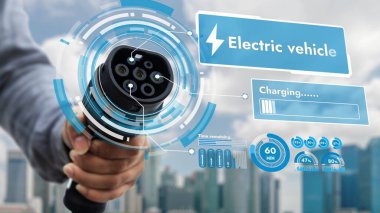 Kameranın önüne odaklanmış EV şarj cihazı bulanık şehir manzaralı akıllı dijital batarya durum hologramını gösterir. Alternatif temiz enerji kullanan EV araba şarjı CO2 salınımını azaltıyor. İnceleyin