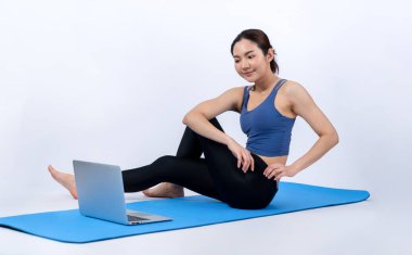İnternetteki videodan alınan talimatlara göre spor kıyafeti giymiş genç Asyalı bir kadın spor egzersizinden önce geriniyor. Sağlıklı atletik bir kadınla vücut egzersizi izole bir zeminde ısınıyor. Kuvvetli