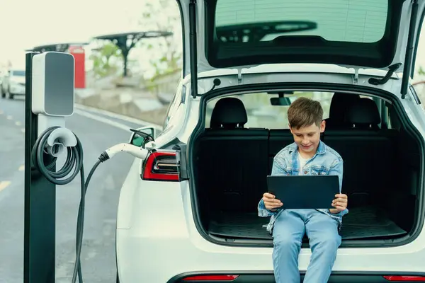 충전소에서 친화적 자동차를 충전하는 태블릿을 사용하여 자동차 트렁크에 가능한 에너지 — 스톡 사진
