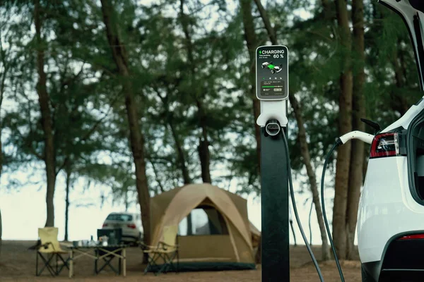 Electric car recharging battery at outdoor EV charging station at natural vacation campsite, alternative and sustainable energy technology eco-friendly car with holiday and travel concept. Perpetual