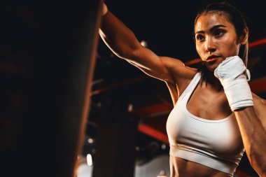 Asyalı kadın Muya Thai boksör eğitimi, spor salonunda kum torbasına yumruk atma. Sağlıklı spor ve spor yaşam tarzı, boks maçı için güç ve dayanıklılık eğitimi. Impetus