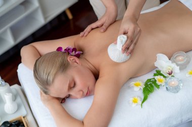 Sıcak bitkisel top spa masaj vücut tedavisi, masör kadın vücuduna nazikçe şifalı bitki torbası bastırıyor. Aromaterapi dinlenme sükuneti ve sükuneti kaplıca salonundaki atmosferi aydınlatıyor. Sessiz.