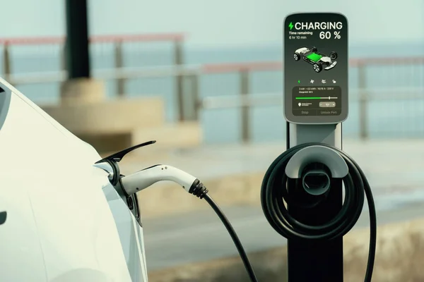 Electric car recharging battery at outdoor EV charging station for road trip or car traveling by the seascape, alternative and sustainable energy technology for eco-friendly car. Perpetual