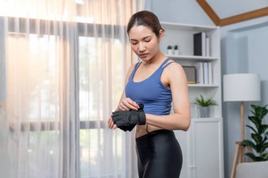 Genç Asyalı kadın portresi spor kıyafetleriyle evde egzersiz yapmadan önce kendini hazırlıyor. Oturma odasında ev içi fitness antrenmanı. Kuvvetli