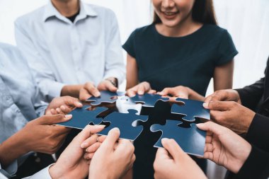 Çeşitli şirket çalışanları, ortaklık ve takım çalışmasını temsil etmek için bulmaca parçalarını birleştirerek ofiste işbirliği yapıyor. Yapboz 'u birleştirerek iş dünyasındaki birlik ve sinerji. Uyum