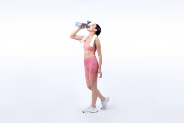 Atletik ve sportif Asyalı kadın yoğun kardiyo antrenmanından sonra dinleniyor ve su içiyor. Stüdyoda sağlıklı egzersiz ve vücut bakımına uygun yaşam tarzı takibi izole edilmiş bir arka plan. Kuvvetli