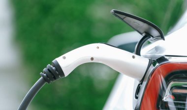 Elektrikli araç portuna bağlı EV şarj prizi kolu şarj istasyonundan şarj oluyor. Modern tasarlanmış EV araba ve daha iyi bir gelecek için temiz enerji sürdürülebilirliği. Panorama Senkronları