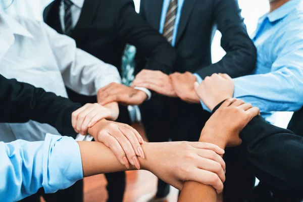 Multicultural business people holding hand together in circle. Unity teamwork in office business workplace. Diverse ethnic office worker engaged in team building. Meticulous