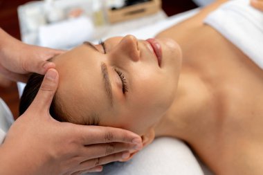 Kafkasyalı kadın stres önleyici kafa masajından ve lüks tatil beldesi ya da otel spa salonundaki modern ışık ortamında yüz güzelliği eğlencelerini şımartmaktan hoşlanıyor. Sessiz.