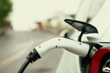 Kapalı EV şarj kolu fişe takıldı veya elektrikli arabaya bağlandı, EV araba aküsünü temiz çevre için sıfır CO2 emisyonu ile alternatif ve sürdürülebilir enerjiyle şarj etti. Kalıcı