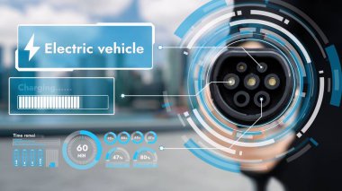 Kameranın önüne odaklanmış EV şarj cihazı bulanık şehir manzaralı akıllı dijital batarya durum hologramını gösterir. Alternatif temiz enerji kullanan EV araba şarjı CO2 salınımını azaltıyor. İnceleyin