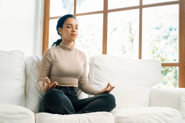 Genç Afrikalı Amerikalı kadın, zihinsel sağlık gücünü ve huzur dolu güzel yaşamı geliştirmek için ev oturma odasında çok dikkatli meditasyon yapıyor.