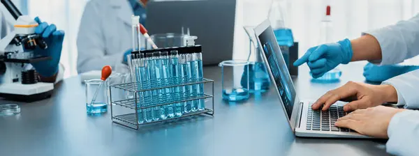 科学者の専門グループは 新しいワクチン薬や抗生物質の画期的な開発とラップトップ上でのテスト結果を研究するために 医学研究所で化学実験や研究を行います — ストック写真