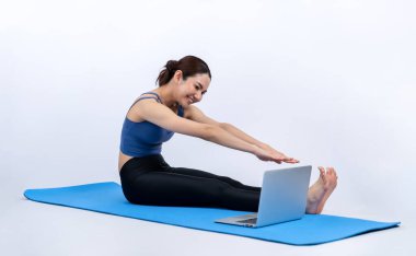 İnternetteki videodan alınan talimatlara göre spor kıyafeti giymiş genç Asyalı bir kadın spor egzersizinden önce geriniyor. Sağlıklı atletik bir kadınla vücut egzersizi izole bir zeminde ısınıyor. Kuvvetli