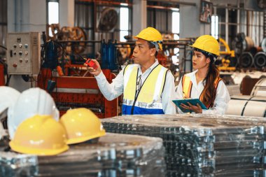 Fabrika ustabaşı ve mühendis çelik makinesi ve ağır endüstriyel malzeme kalitesinde ürün teftişi yapıyor. Makine güvenliği ve kalite kontrollü metal levha üretimi. Örnek gösteriliyor