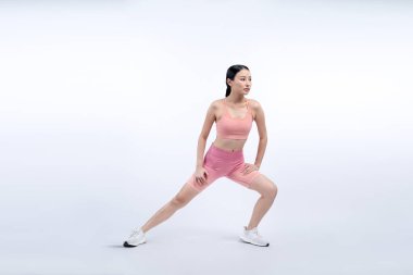 Spor giyimli çekici Asyalı kadın spor egzersizlerinden önce esneme hareketleri yapıyor. Stüdyo çekimlerinde ısınan atletik bir kadınla sağlıklı vücut bakımı egzersizi. Kuvvetli