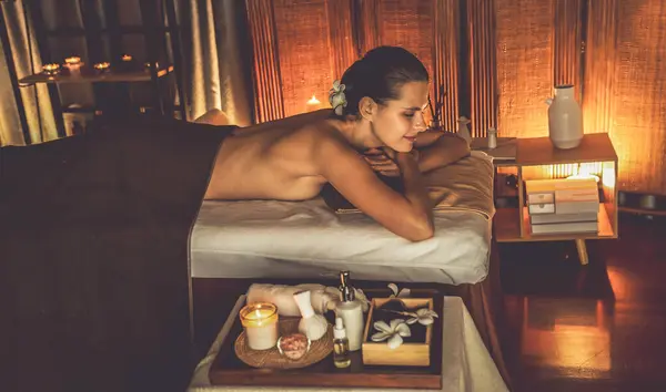 白种人女性顾客喜欢在豪华度假胜地或宾馆里 在温暖的烛光下享受轻松的抗压力温泉按摩和美肤娱乐休闲 — 图库照片