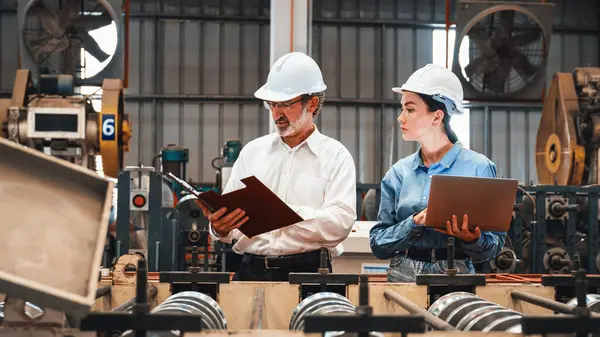 厂长与助手一起用笔记本电脑对钢铁工业机器进行检验 体现了在金属加工生产中作为机械工程检验主管的领导作用 — 图库照片