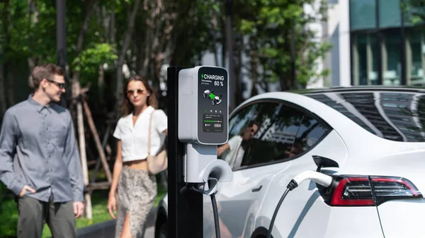 Młoda Para Podróżuje Elektrycznym Ładowaniem Samochodów Elektrycznych Zielonym Zrównoważonym Ogrodzie — Zdjęcie stockowe