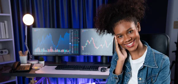 年轻的非洲裔美国女商人面带微笑 身穿牛仔裤衬衫 坐在椅子上 面对着股票交易所的市场背景 投资博客的概念 节衣店 — 图库照片