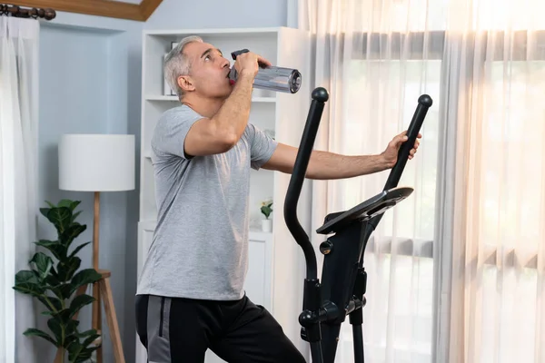 Active Senior Man Running Elliptical Running Machine Drinking Water Home — Stock Photo, Image