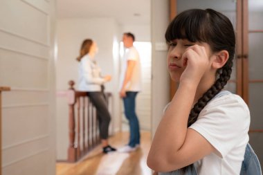 Stresli ve mutsuz genç kız arka planda tartışırken gözyaşlarını siliyor. Evde aile içi şiddet ve travmatik çocukluk depresyona dönüşür. Eşzamanlama