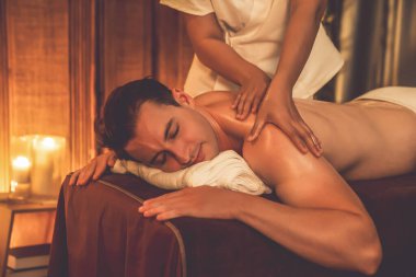 Beyaz erkek müşteri stres önleyici spa masajının keyfini çıkarıyor ve lüks otel ya da oteldeki ortam kaplıcalarında sıcak mum ışığında güzellik teniyle eğleniyor. Sessiz.