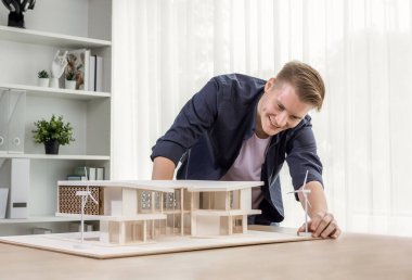 Mimari tasarımcı zarif ev modelini inceler, inşaat planının geliştirilmesi için yapı tasarımını gözden geçirir. Mimari tasarımda yaratıcılık ve yenilik. Tekrarlama
