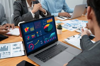 Çok ırklı analist ekibi toplantı masasındaki finansal verileri analiz etmek için BI Fintech yazılımı kullanıyor. Finansal konsol veri ekranında pazarlama göstergesi için analiz edilmiş grafikle birlikte. Uyum