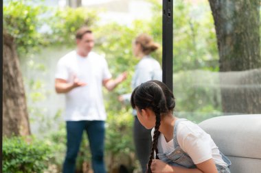 Stresli ve mutsuz genç kız arka planda ebeveynleri tartışırken köşede ağlayıp üzülüyor. Evde aile içi şiddet ve travmatik çocukluk depresyona dönüşür. Eşzamanlama