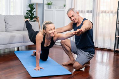 Spor giyim sektöründe aktif olan mutlu çift destekleyici ve evde yoga duruşunda birlikte yardımcı oluyorlar. Yoga egzersizi yapan sağlıklı bir erkek ve kadın yaşam tarzı. Etki