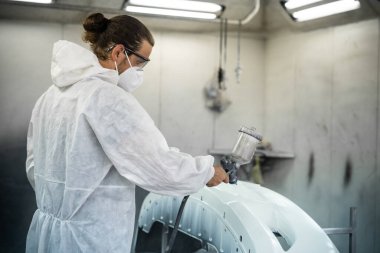 Koruyucu ekipmanlı otomotiv işçisi araba kaportasına sprey tabanca ya da oda atölyesindeki solunum boyasıyla renk boyası uyguluyor. Tamir için araba boyama servisi. Oxus.