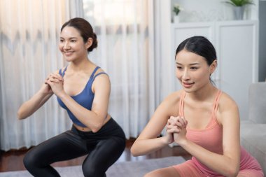 Egzersiz arkadaşı ya da antrenörü olan enerjik bir kadın evde egzersiz yapıyor. Genç atletik Asyalı kadın dayanıklılığı ve dayanıklılık antrenmanı..