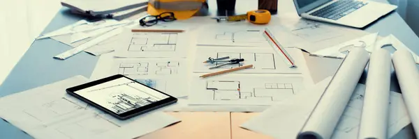 Architectural designed building blueprint layout and engineer tool for designing blueprint with contractor project document on engineer workspace table in office with safety helmet or hardhat. Insight