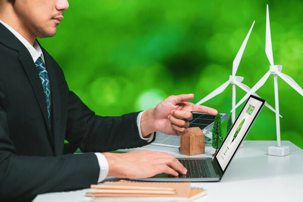 Бизнесмен, работающий в офисе, разрабатывает план или проект по экологически чистой альтернативной энергии с отображением технологии солнечных батарей на экране компьютера для более экологичной среды, как часть усилий КСО. Ор