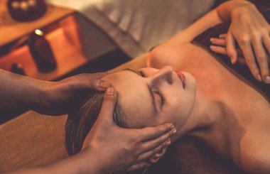 Beyaz kadın stres önleyici kafa masajı yapmaktan ve lüks otel veya otelde sıcak mum ışığında yüz güzelliği eğlencesi yapmaktan zevk alıyor. Sessiz.