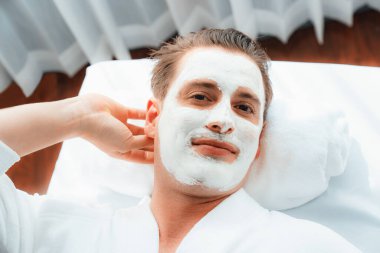 Kaplıca salonunun sakin atmosferi, insan müşterisi modern gün ışığında lüks yüz kremi masajıyla kendini yenileme zevkine kapılıyor. Yüz bakımı ve güzellik konsepti. Sessiz.