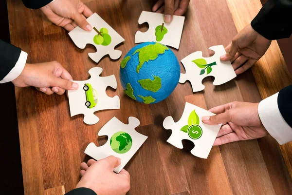 Cohesive group of business people holding eco icon jigsaw puzzle pieces around globe Earth as eco corporate responsibility for community and sustainable solution for greener Earth. Quaint