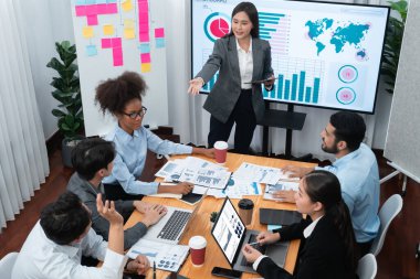 Modern toplantı odasındaki TV ekranında veri analizi paneliyle üst görünüm iş sunumu. İş adamlarının iş pazarlama stratejisini planlamak için beyin fırtınası yapması ya da birlikte çalışması. Uyum