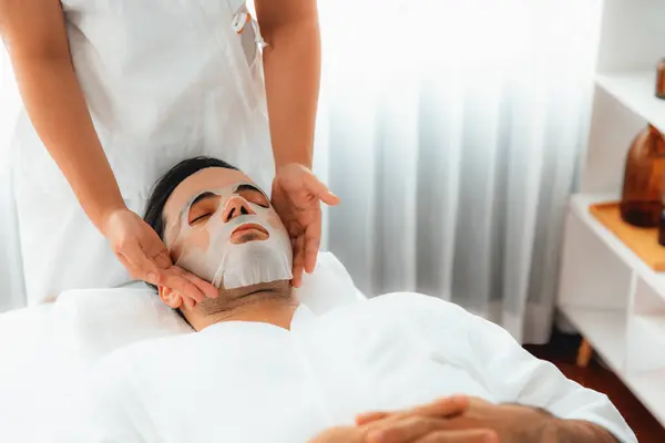 Serene modern daylight ambiance of spa salon, woman customer indulges in rejuvenating with facial skincare mask. Facial skin treatment and beauty cosmetology procedure for face. Quiescent