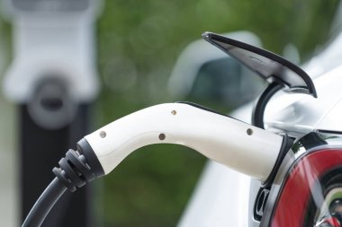 Elektrikli araç portuna bağlı EV şarj prizi kolu şarj istasyonundan şarj oluyor. Modern tasarlanmış EV araba ve daha iyi bir gelecek konsepti için temiz enerji sürdürülebilirliği. Eşzamanlama