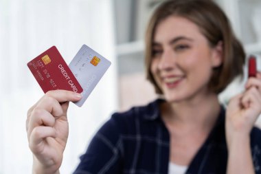 Genç mutlu kadın internetten alışveriş yaparak ürün satın alırken aynı zamanda internet üzerinden online ödeme sistemi ile çevrimiçi mağaza platformundan en yüksek siber güvenlik tarafından korunan ürünler sipariş ediyor.